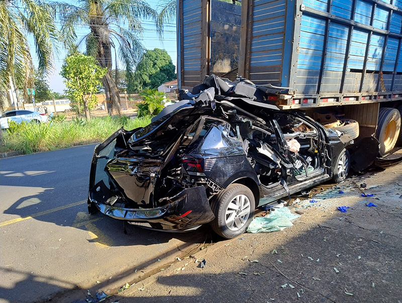 Carro tem perda total ao chocar em traseira de caminhão e motorista escapa da morte